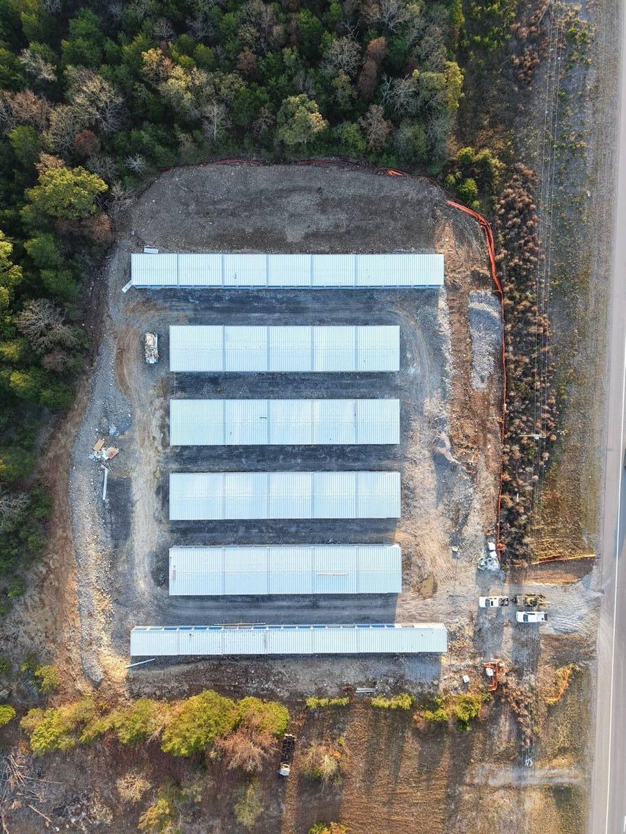 Drone view from directly above the site: six long storage buildings side by side, the outer two longer
